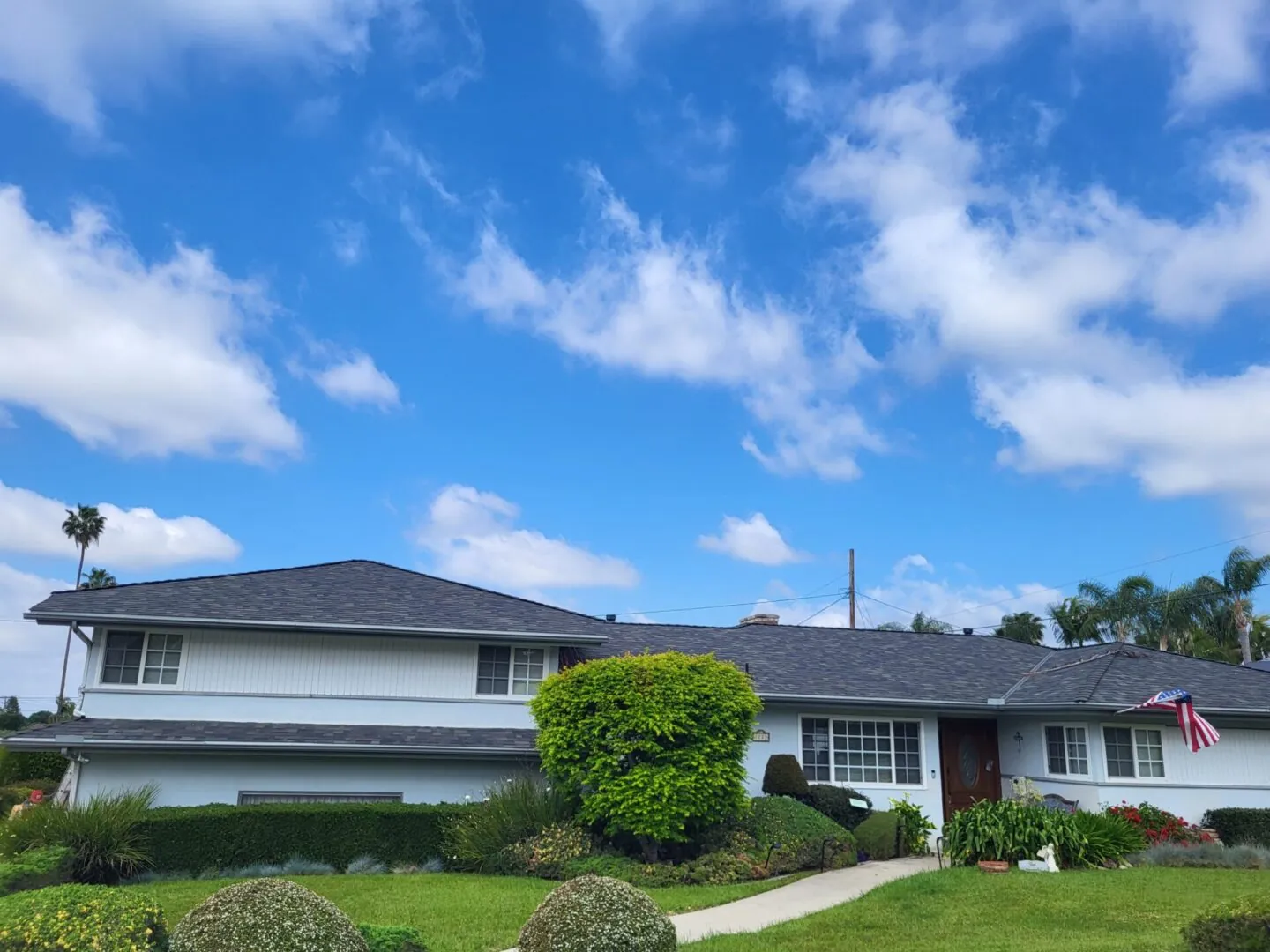 Two-story home with a new charcoal shingle roof under a blue sky